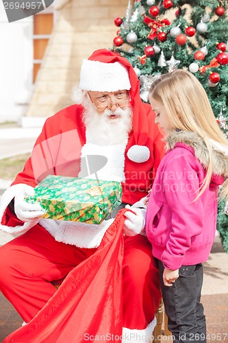 Image of Santa Claus Giving Present To Girl