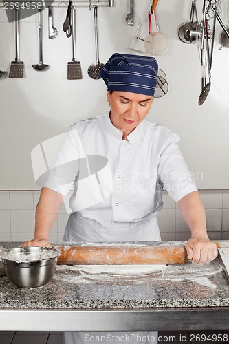 Image of Female Chef Rolling Dough At Kitchen Counter