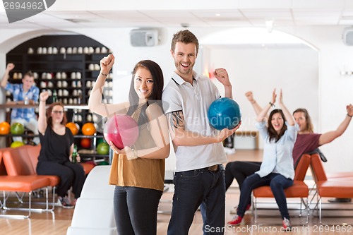 Image of Excited Man And Woman With Bowling Balls in Club