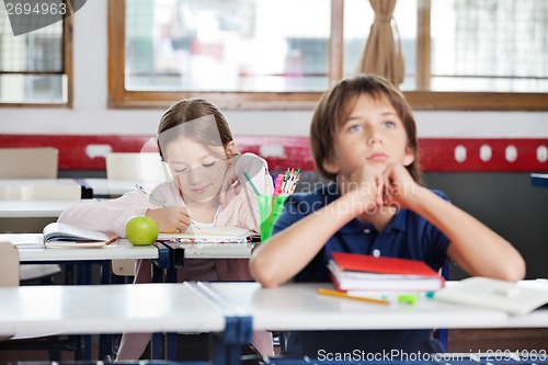 Image of Schoolgirl Writing Notes In Classroom