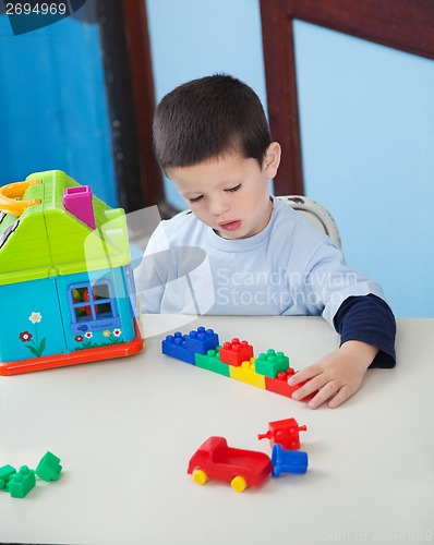 Image of Boy Playing With Toys At Desk In Preschool