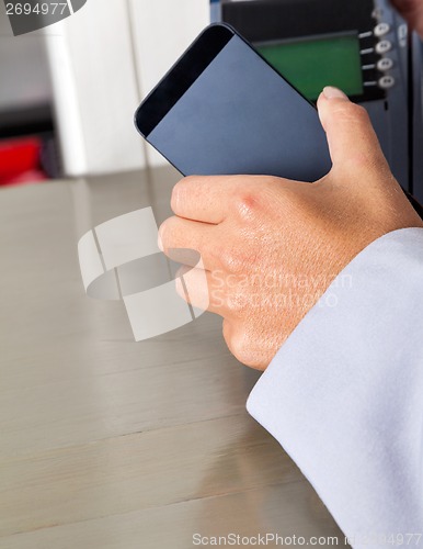 Image of Woman's Hand Placing Smartphone Over Electronic Reader