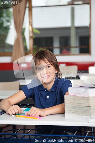 Image of Schoolboy With Books And Globe At Desk