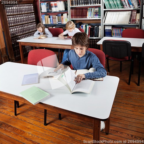 Image of Little Boy Reading Books In Library