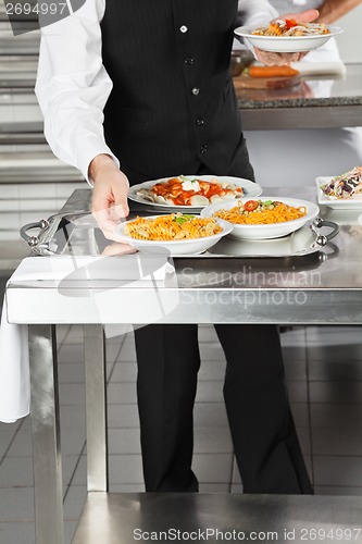 Image of Waiter Placing Pasta Dishes On Tray