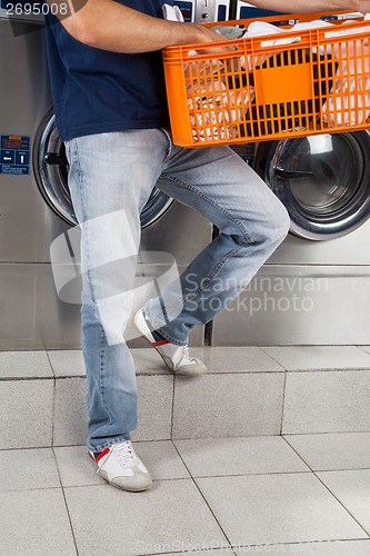 Image of Man Holding Basket Of Clothes In Laundry