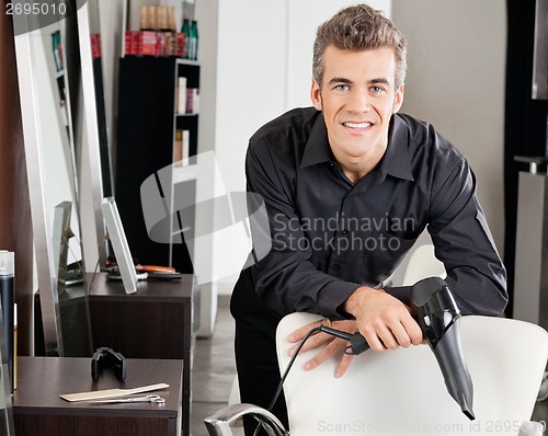 Image of Hairstylist With Blower Leaning On Chair