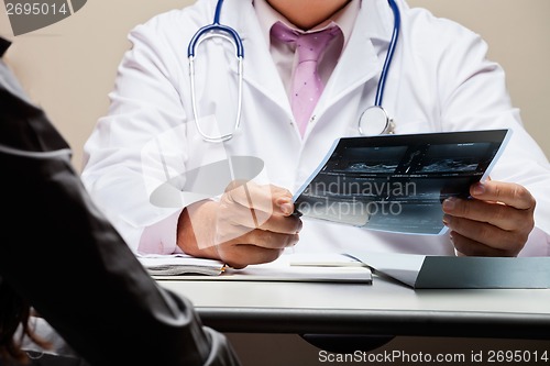 Image of Radiologist At Desk Holding X-ray