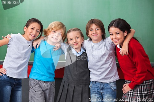 Image of Cute Schoolchildren With Arms Around Standing Together In Classr