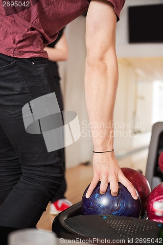 Image of Man Picking Bowling Ball From Rack in Club