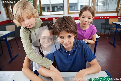 Image of Cute Schoolchildren Using Laptop At Desk