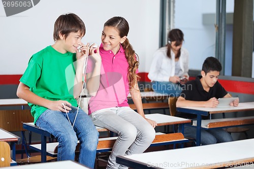 Image of Teenage Boy And Girl Listening Music In Classroom