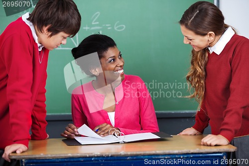 Image of Teacher Discussing With Students At Desk
