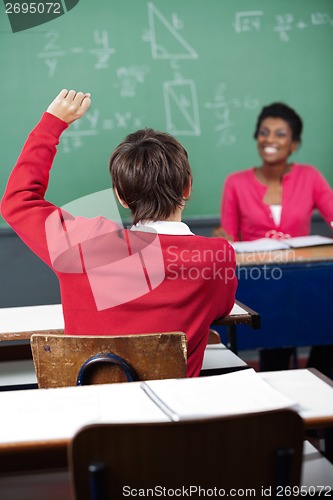 Image of Teenage Schoolboy Raising Hand At Desk