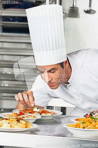 Image of Male Chef Garnishing Pasta Dishes
