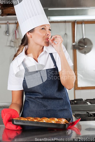 Image of Female Chef With Baked Bread Licking Finger