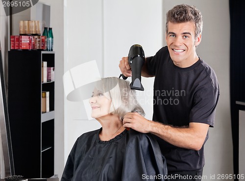 Image of Male Hairdresser With Dryer Setting Customer's Hair