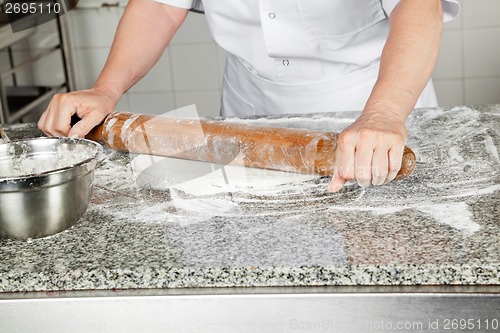 Image of Female Chef Rolling Dough In Kitchen