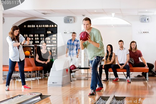 Image of Man Bowling With Friend Photographing At Club