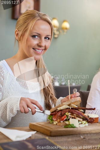 Image of Young Woman Eating Sandwich In Restaurant