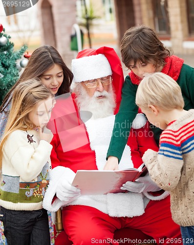 Image of Santa Claus And Children Reading Book