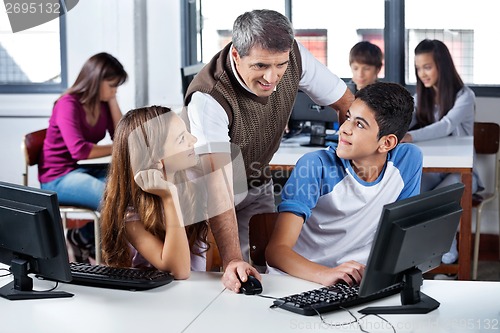 Image of Teacher Using Computer With Students In Classroom