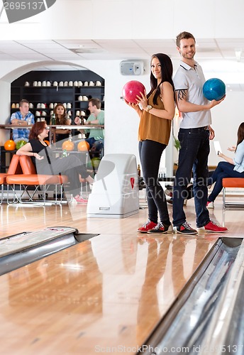 Image of Man And Woman Standing With Bowling Balls in Club