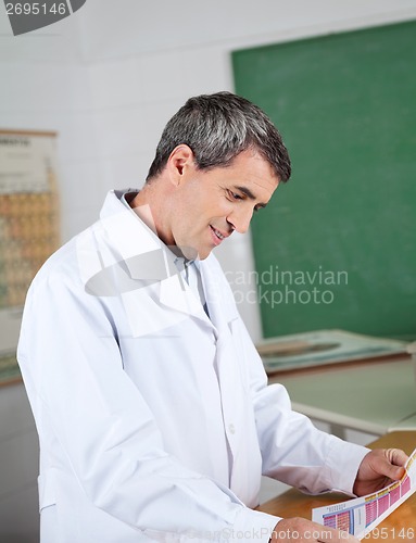 Image of Professor Reading Paper At Desk In Lab