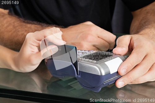 Image of Hand Swiping Credit Card Through Terminal At Salon
