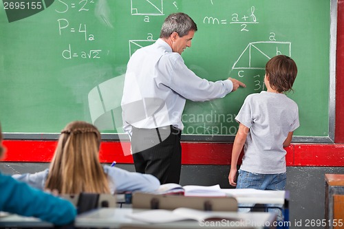 Image of Teacher Assisting Schoolboy While Solving Mathematics