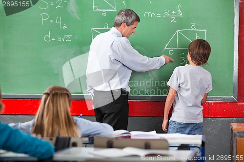 Image of Teacher Assisting Schoolboy While Solving Mathematics