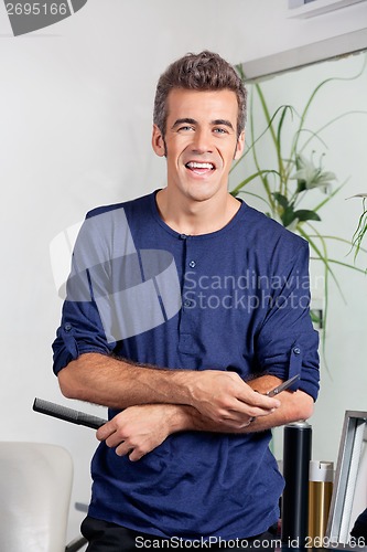 Image of Male Hairdresser Holding Scissors And Comb In Salon