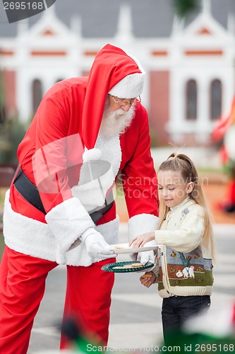 Image of Girl Taking Cookies From Santa Claus