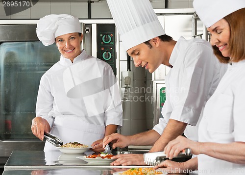 Image of Female Chef With Colleagues Working In Kitchen