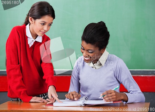 Image of Schoolgirl Asking Question To Female Teacher At Desk