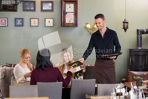 Image of Young Waiter Giving Menu To Female Customers