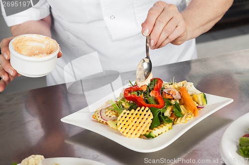 Image of Female Chef Garnishing Dish At Counter