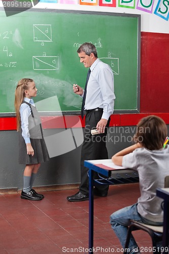 Image of Side View Of Teacher And Girl Looking At Each Other Against Boar