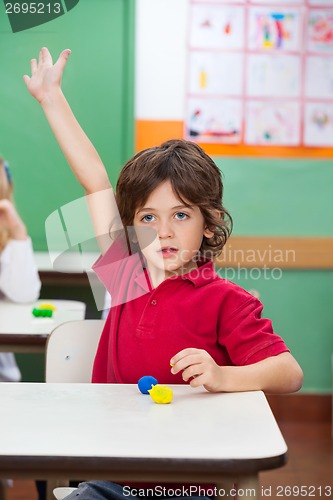 Image of Boy With Hand Raised Sitting At Desk