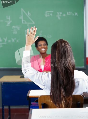 Image of Rear View Of Schoolgirl Raising Hand In Classroom