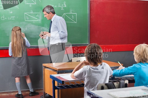 Image of Little Schoolgirl Solving Mathematics On Board