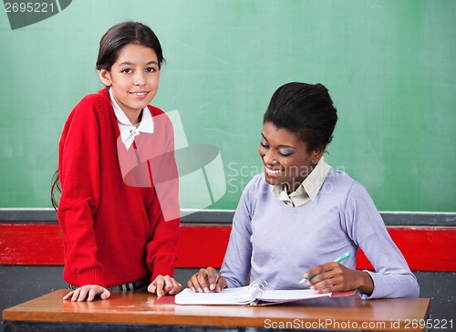 Image of Portrait Of Schoolgirl With Teacher Reading Binder At Desk