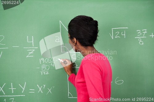 Image of Female Teacher Solving Mathematics On Board