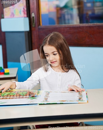 Image of Girl Opening Popup Book At Desk In