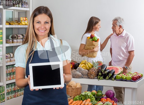Image of Saleswoman Displaying Tablet With Customers In Background