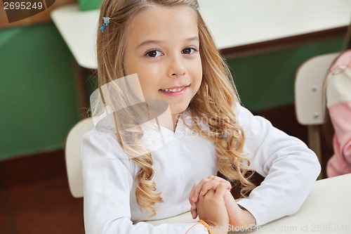 Image of Girl Sitting With Hands Clasped In Classroom