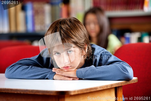 Image of Portrait Of Bored Schoolboy Leaning On Table In Library