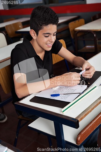 Image of Schoolboy Copying From Cheat Sheet At Desk