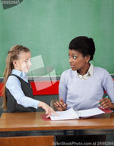 Image of Schoolgirl Pointing In Binder While Teacher Looking At Her