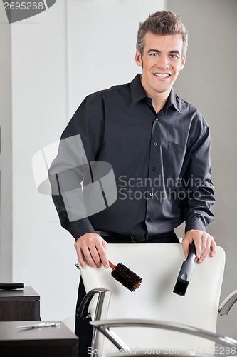 Image of Happy Hairdresser Holding Straightener And Brush